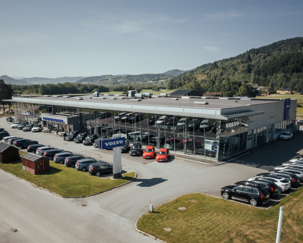 Stor bygning med mye glass med mange biler parkert utenfor
